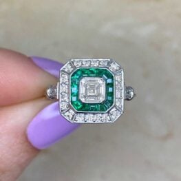engagement ring featuring emeralds and asscher cut diamonds with an open work under gallery